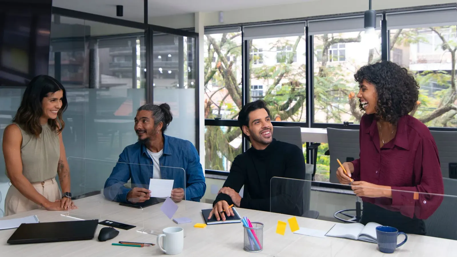 Equipe de vendas conversando em volta da mesa de trabalho num escritório iluminado